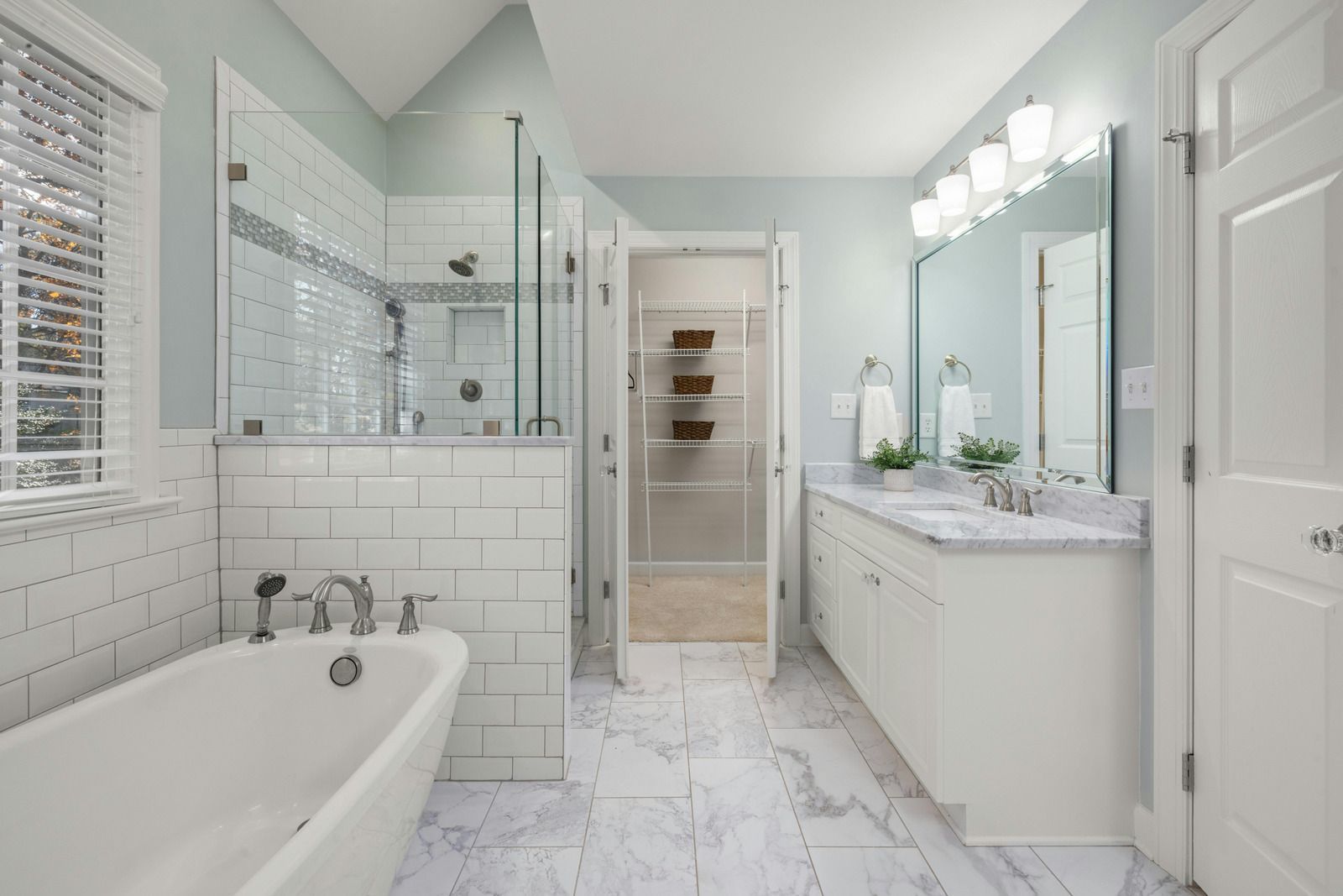 A hand in a yellow rubber glove wipes a white countertop in a tiled bathroom.