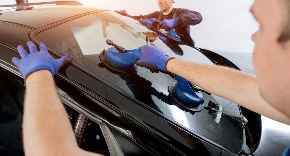 A Man is Installing a Windshield on a Car — Bendigo Windscreens In Bendigo, VIC