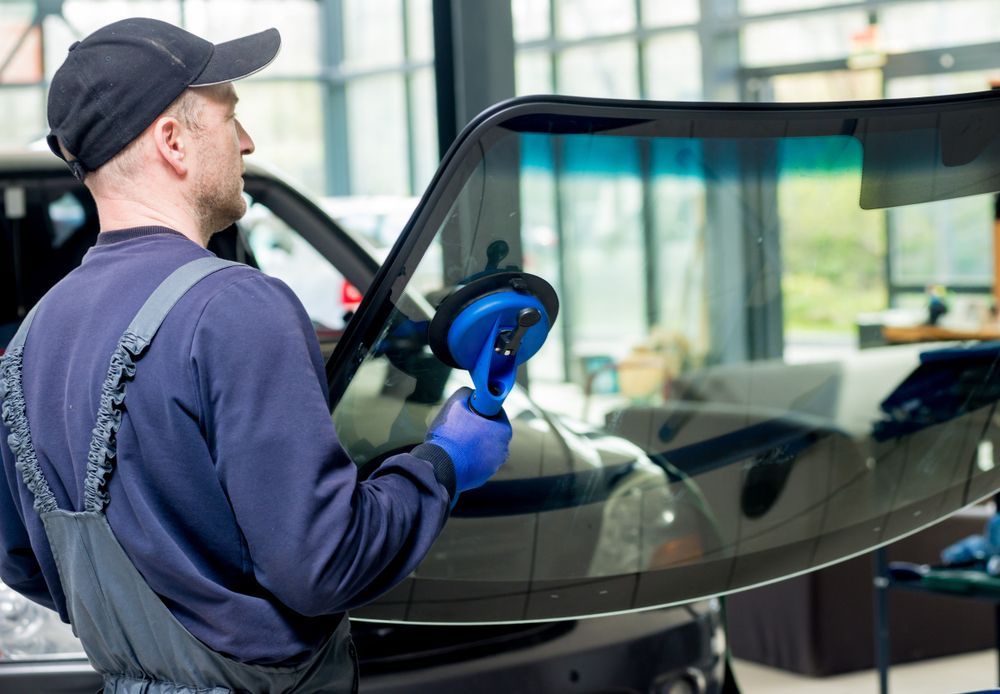 A Man is Installing a Windshield on a Car — Bendigo Windscreens In Bendigo, VIC
