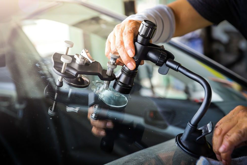 A Man is Fixing a Cracked Windshield on a Car — Bendigo Windscreens In Bendigo, VIC