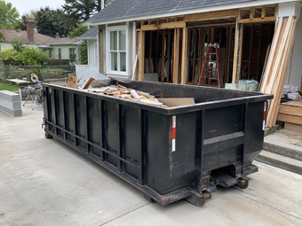 Large open-top roll-off dumpster at a residential renovation project