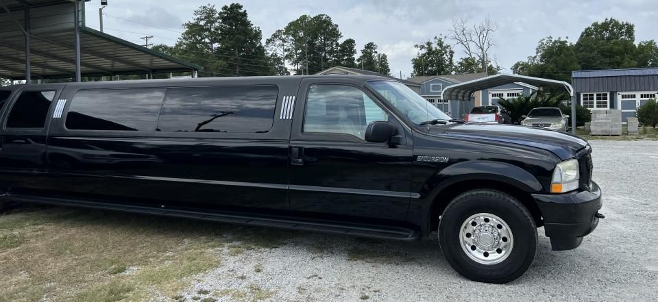 Black stretch limousine parked on a gravel lot under an overcast sky