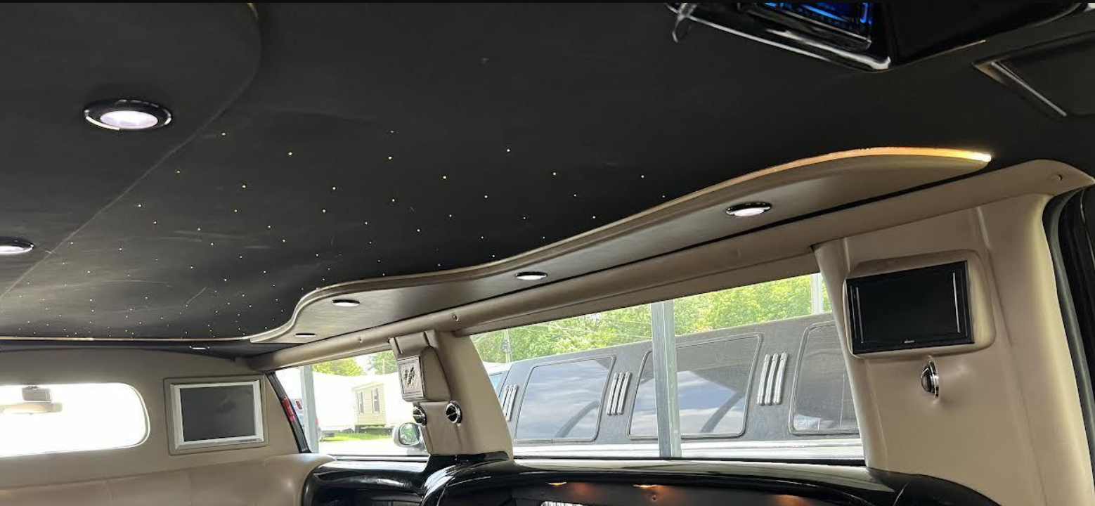 Inside a luxury van with beige leather seats, black ceiling, and windows showing the outdoors