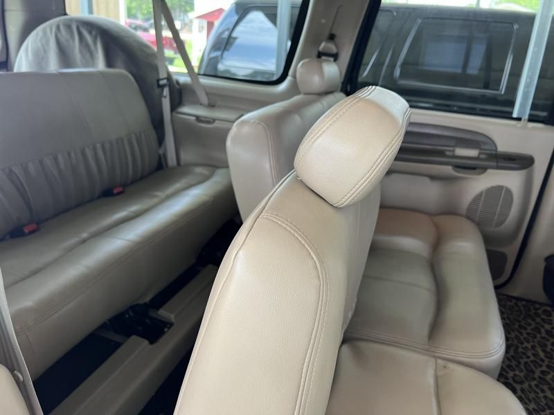 Inside a car, beige leather seats with a gray-covered rear bench are shown from the open side door.