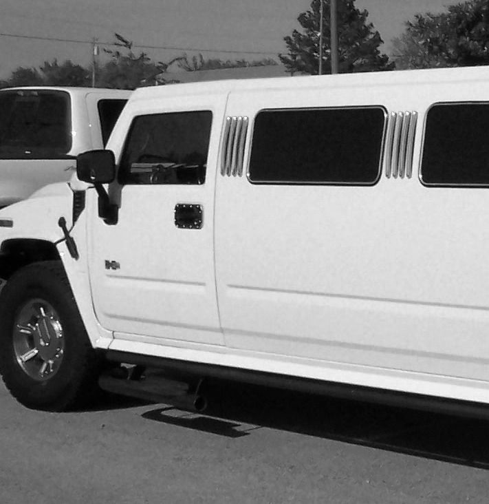 White stretch limousine parked beside a white SUV on a street.