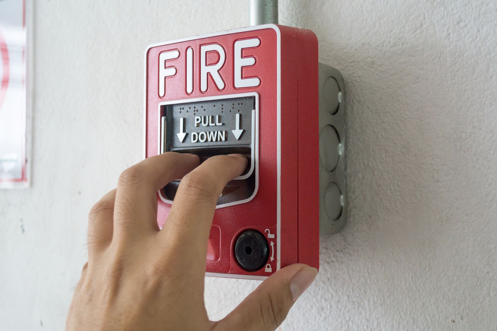 The hand of a man is pulling a fire security installation system installed on a wall.