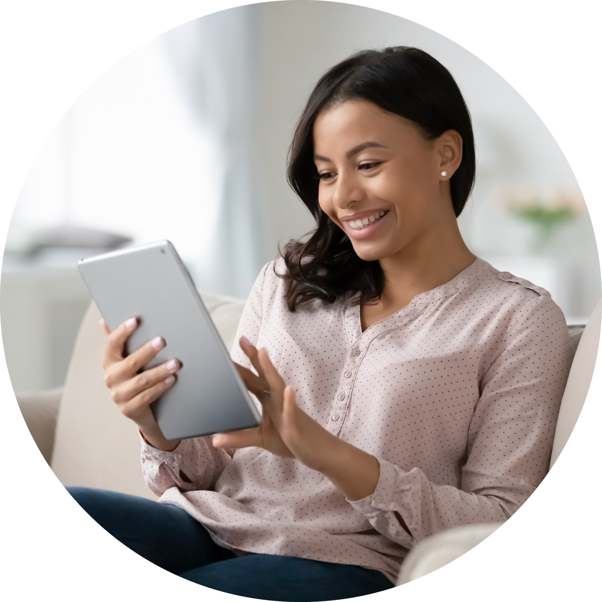 A woman is sitting on a couch using a tablet computer