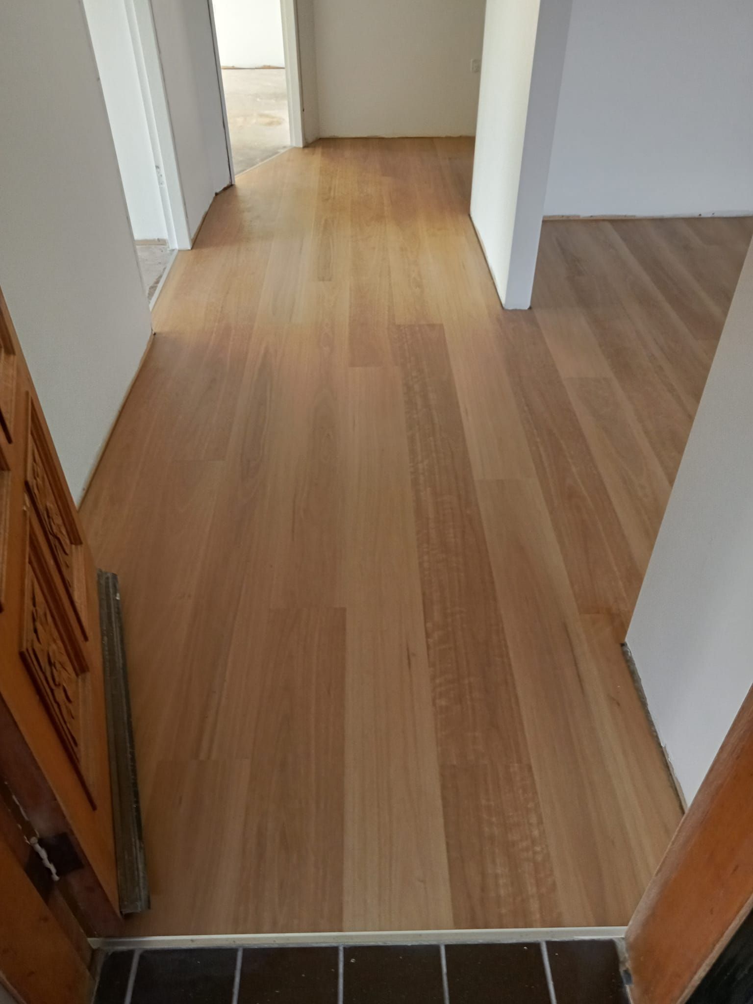 A Hallway With a Wooden Floor and a Door — BLB Flooring Solutions in Central Coast, NSW