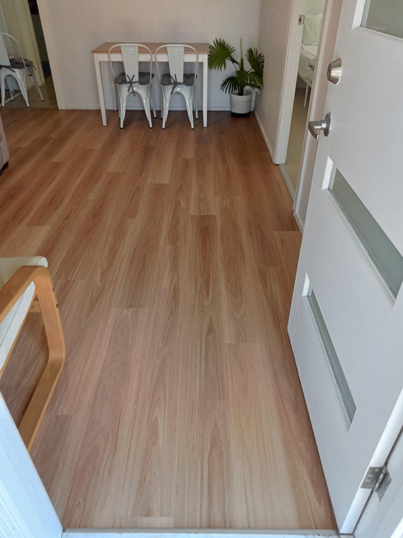 A Wooden Floor in a Living Room With a Table and Chairs — BLB Flooring Solutions in Central Coast, NSW