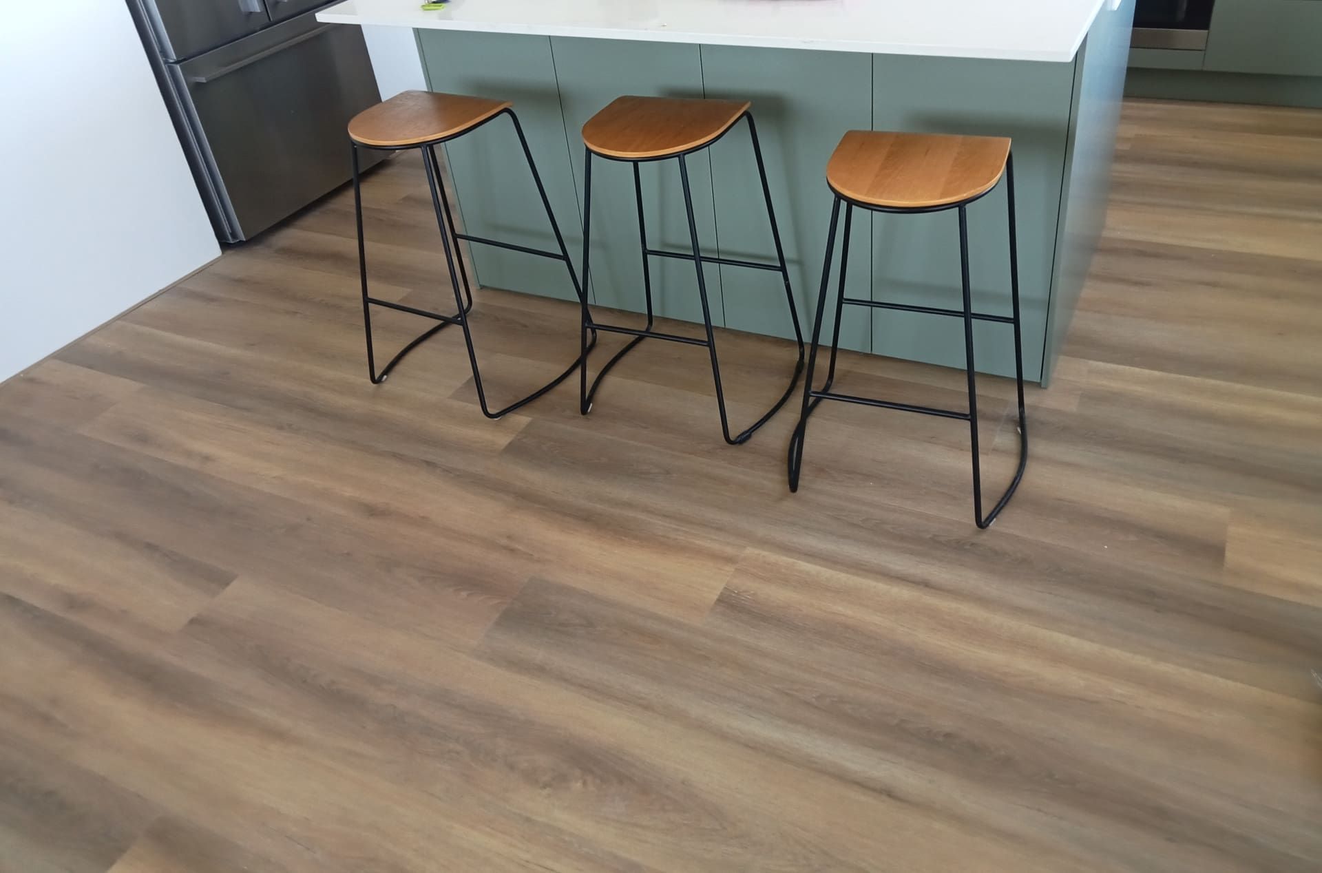 Three Bar Stools Are Sitting on a Wooden Floor in a Kitchen — BLB Flooring Solutions in Central Coast, NSW