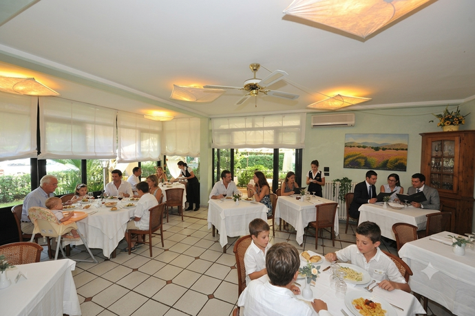 Luminosa sala da pranzo del ristorante con tovaglie bianche, sedie in vimini e grandi finestre con tende.