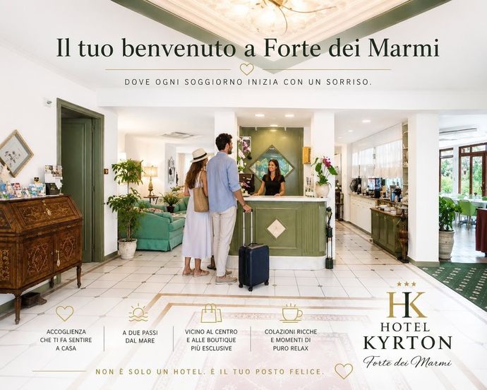 Ingresso coperto dell'edificio con scalini, piante in vaso e porte a vetri sotto una tettoia bianca.