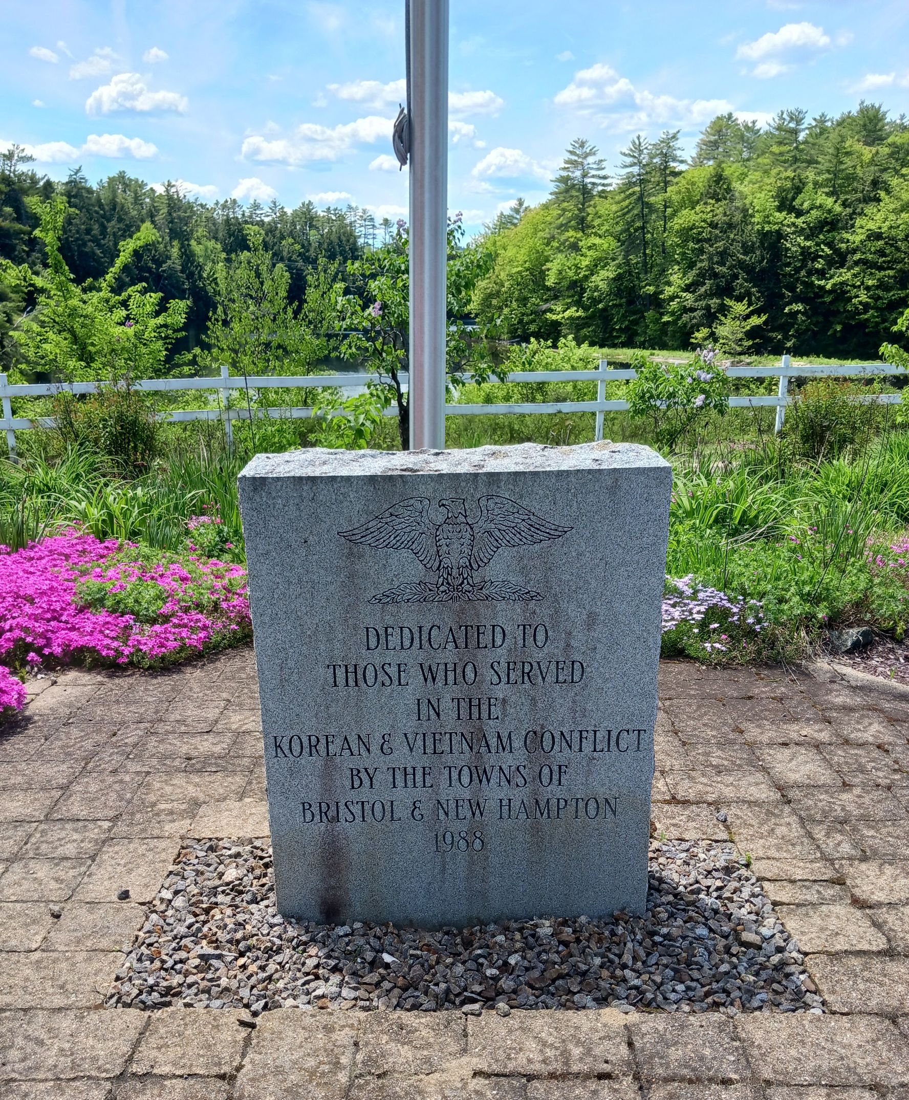 Dirty stone memorial at the base of a flagpole