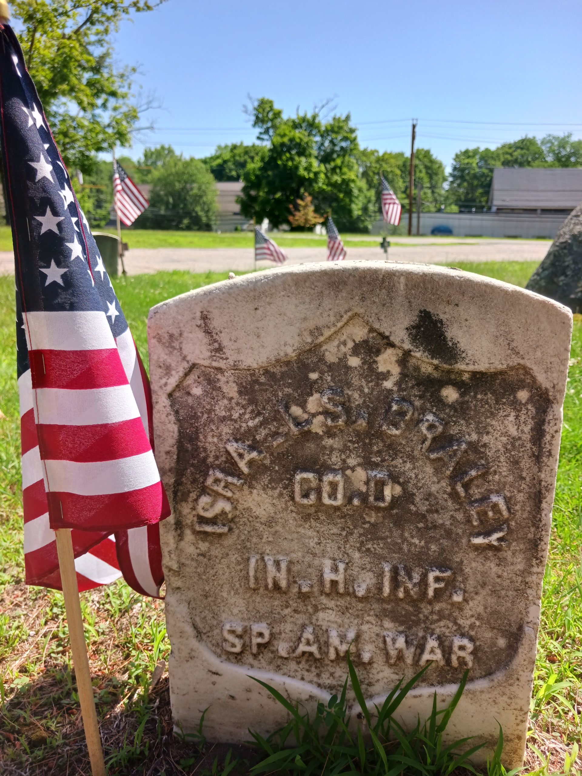 Headstone for Israel Braley, a soldier in the Spanish-American War, marked with a US flag.