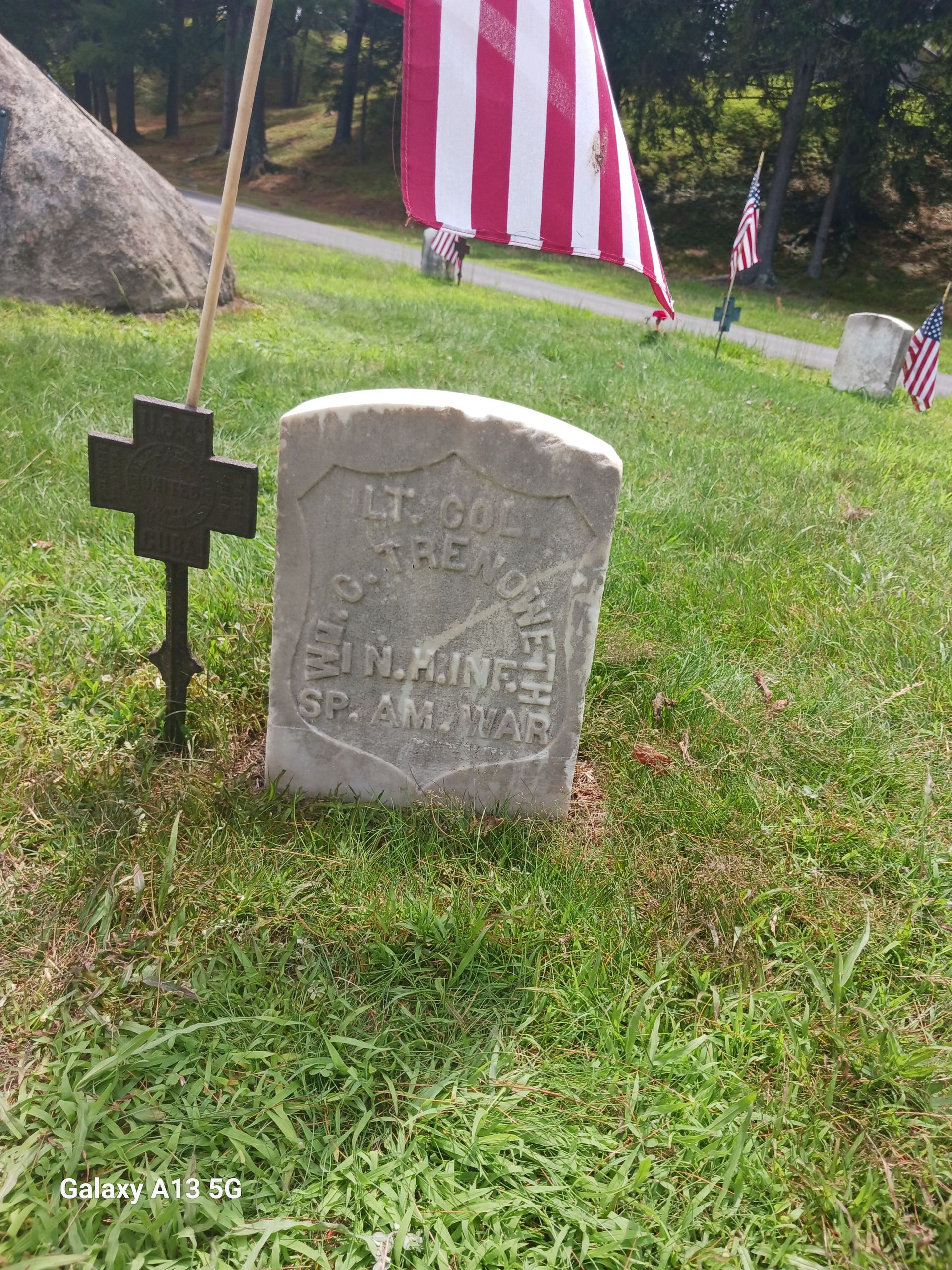 Gravestone of Lt. Col. Wm. Trenowith with a cross and flags in a grassy graveyard setting.