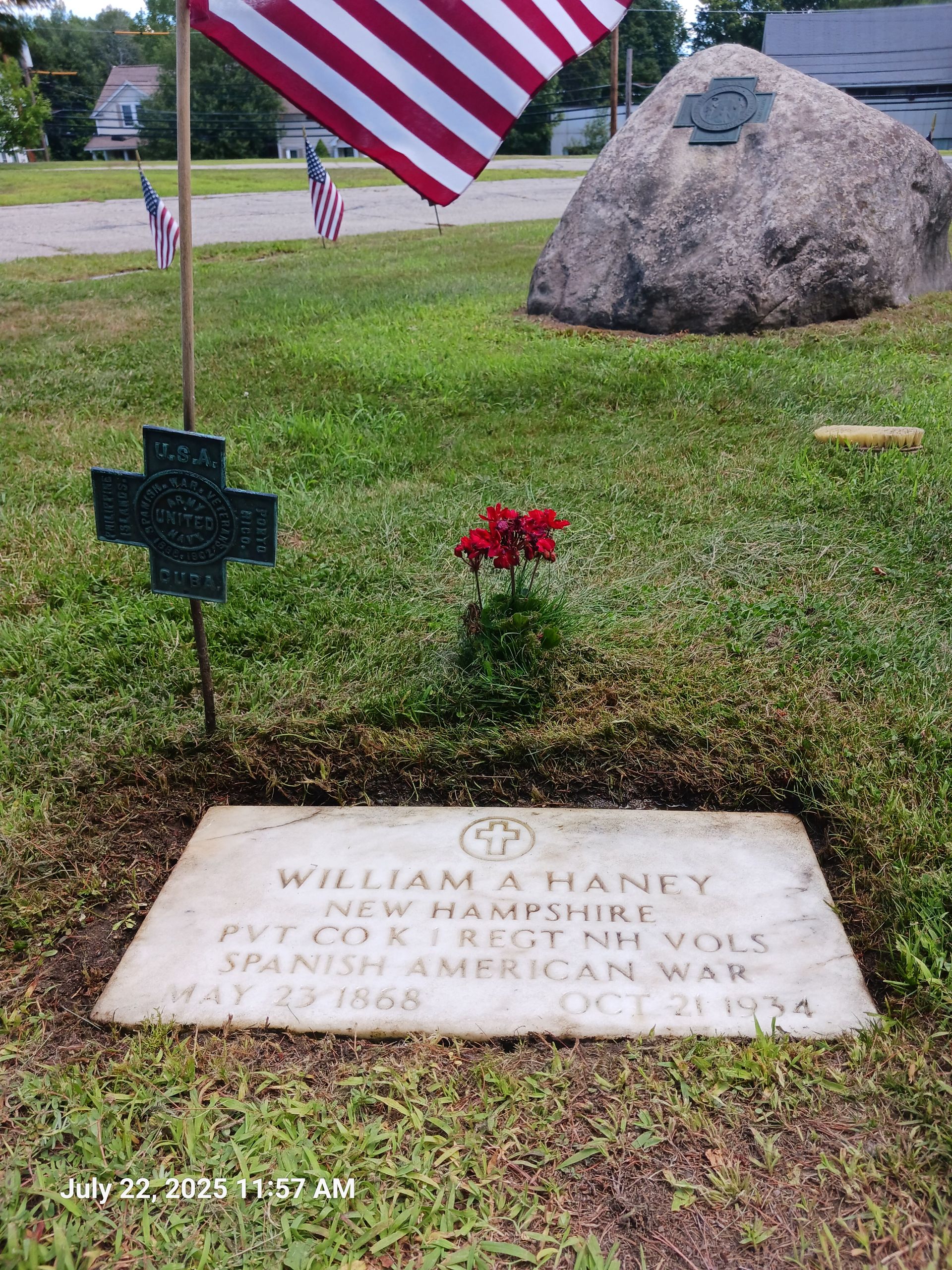 Tombstone of William A. Haney, a veteran of the Spanish-American War, marked with an American flag, a cross, and red flowers.