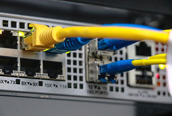 Primer plano de un conmutador de red con cables Ethernet amarillos y azules conectados.