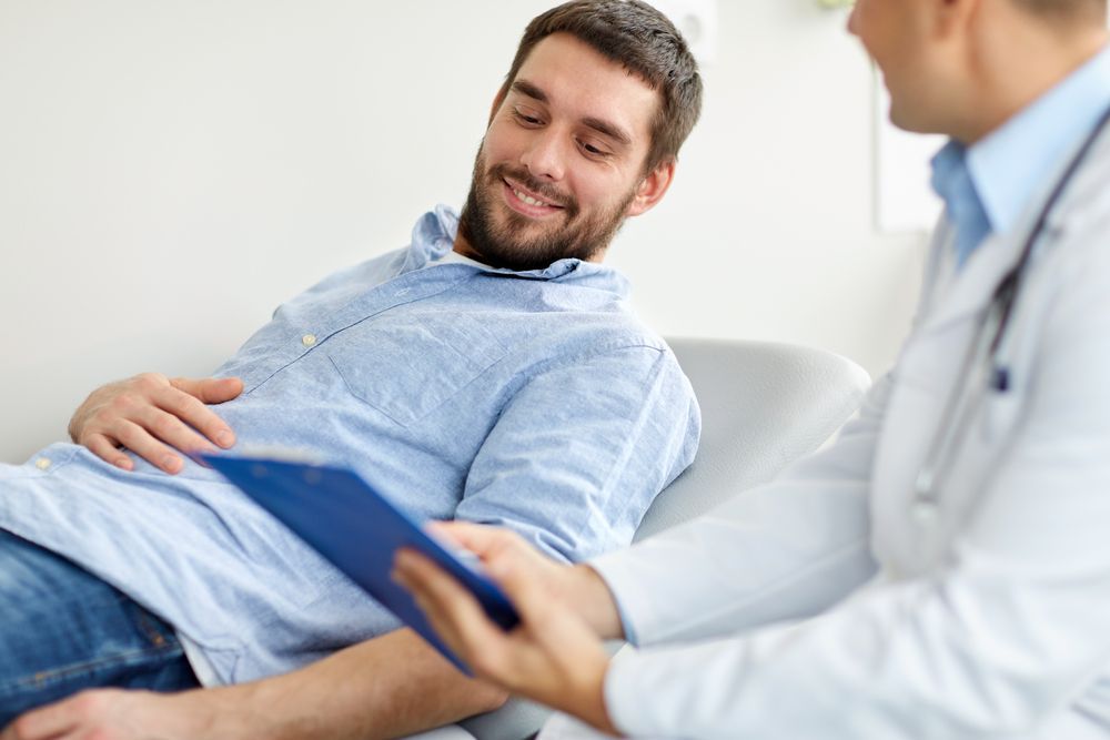 Doctor consulting with a relaxed patient on a couch, holding a clipboard in a bright office