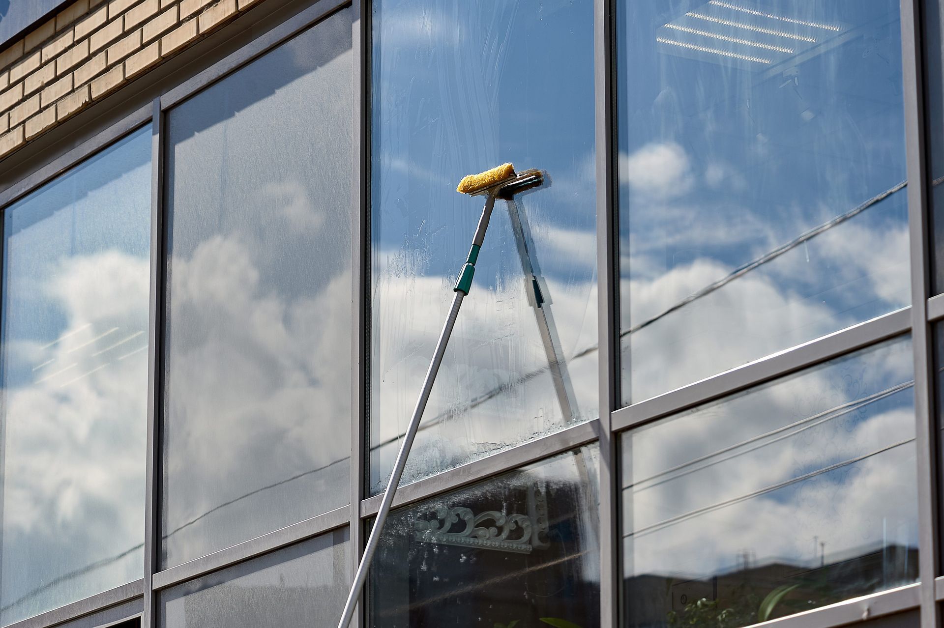A person is cleaning the windows of a building with a brush.