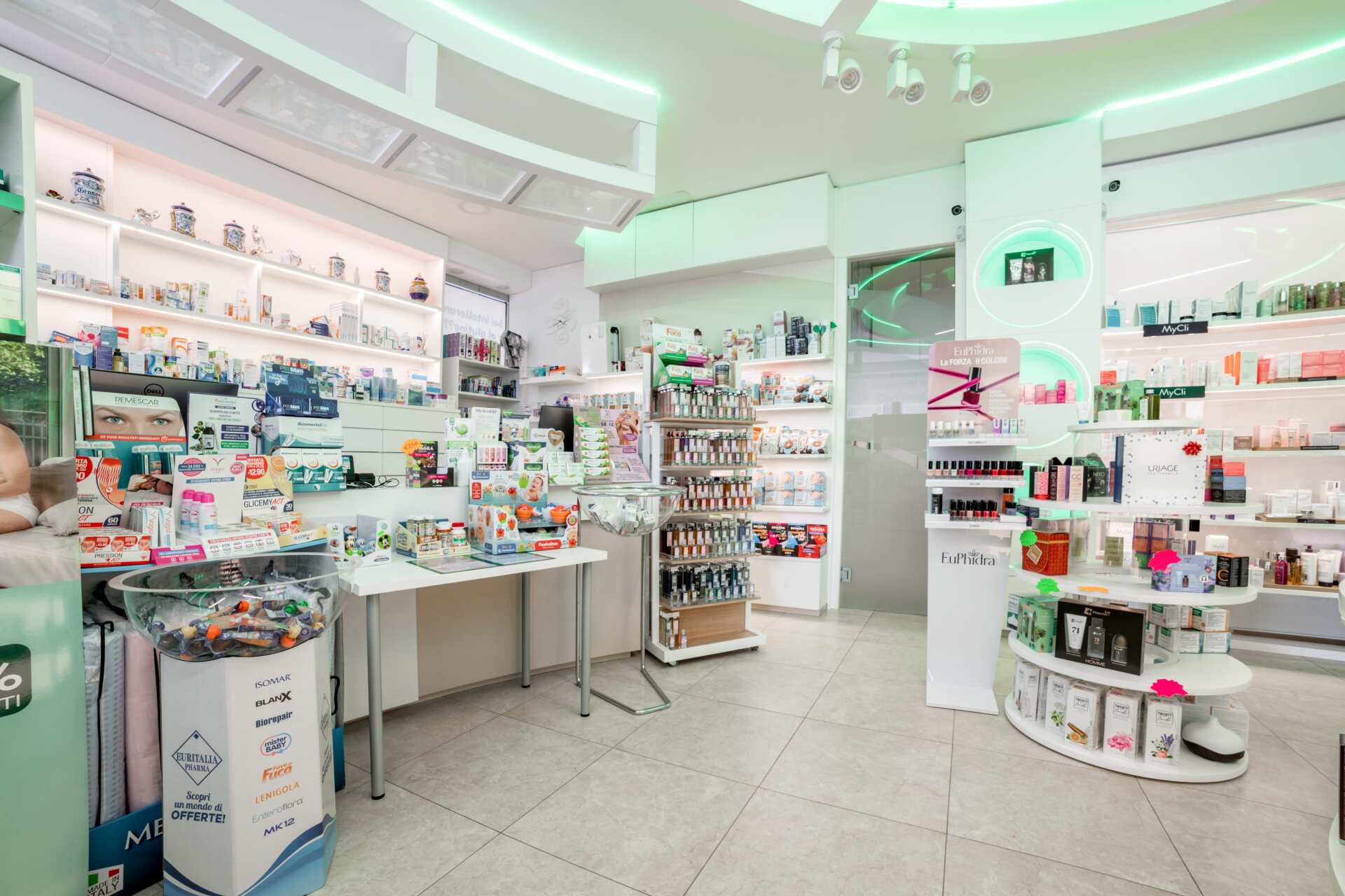 Negozio di cosmetici e prodotti per la cura della pelle luminoso e bianco, con scaffali pieni di prodotti e un tavolo espositivo centrale.