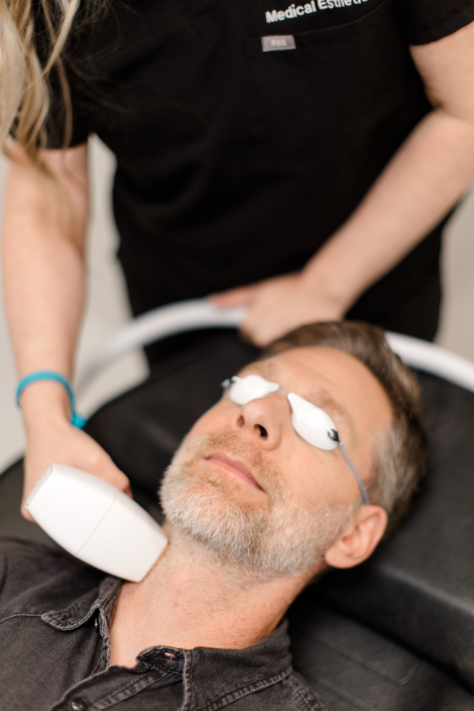 A man with a beard is getting a laser treatment on his neck.