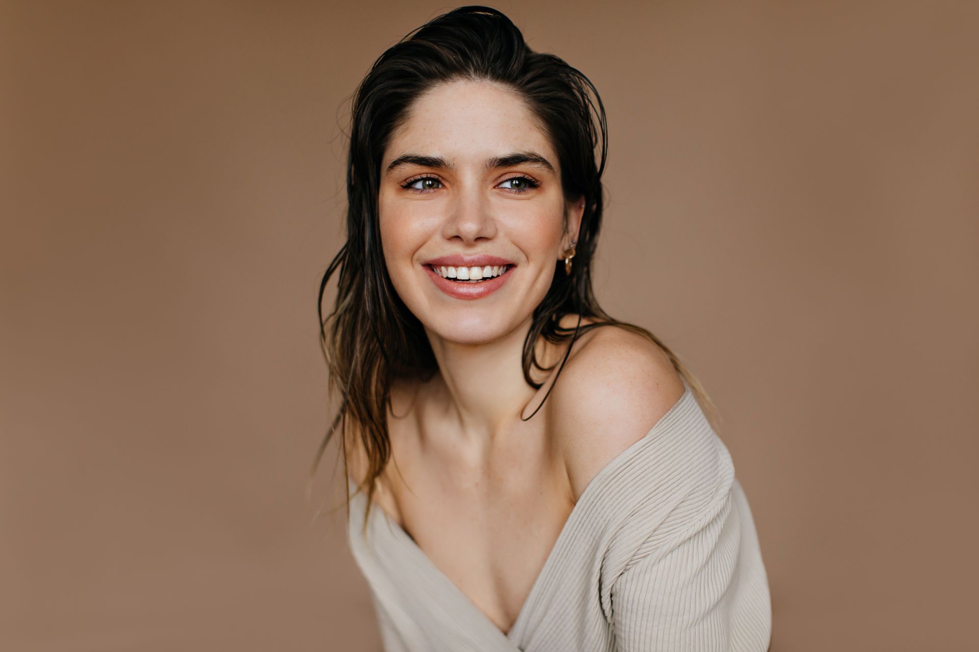 A woman in a sweater is smiling and looking at the camera.