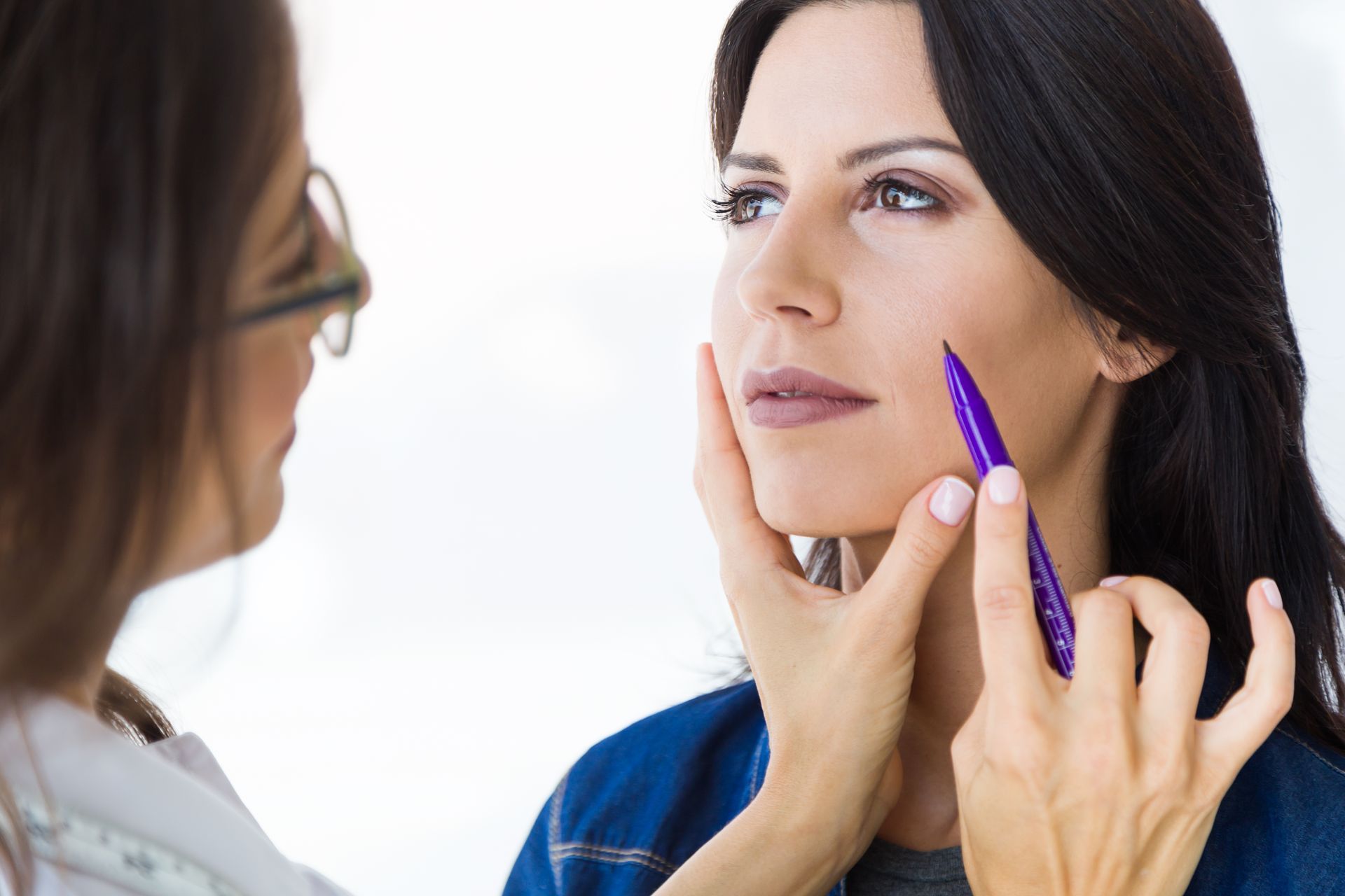 A woman is getting her face measured by a doctor.