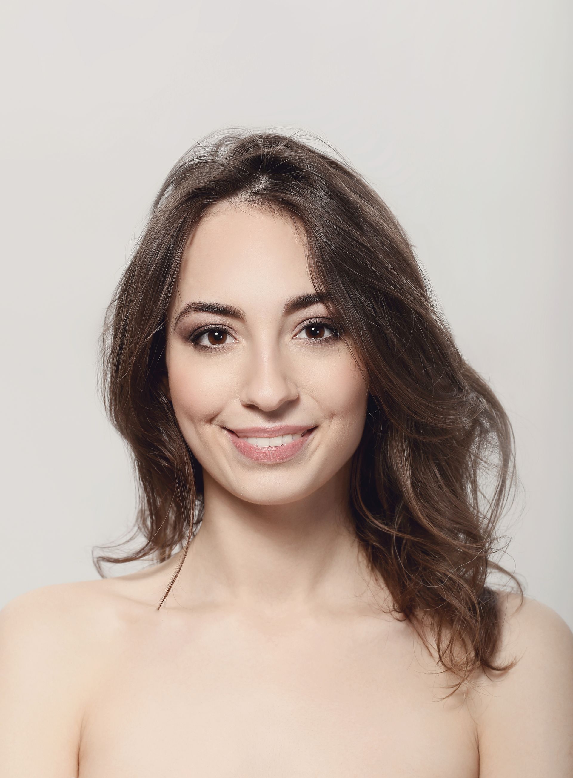 A woman without a shirt is smiling and looking at the camera.