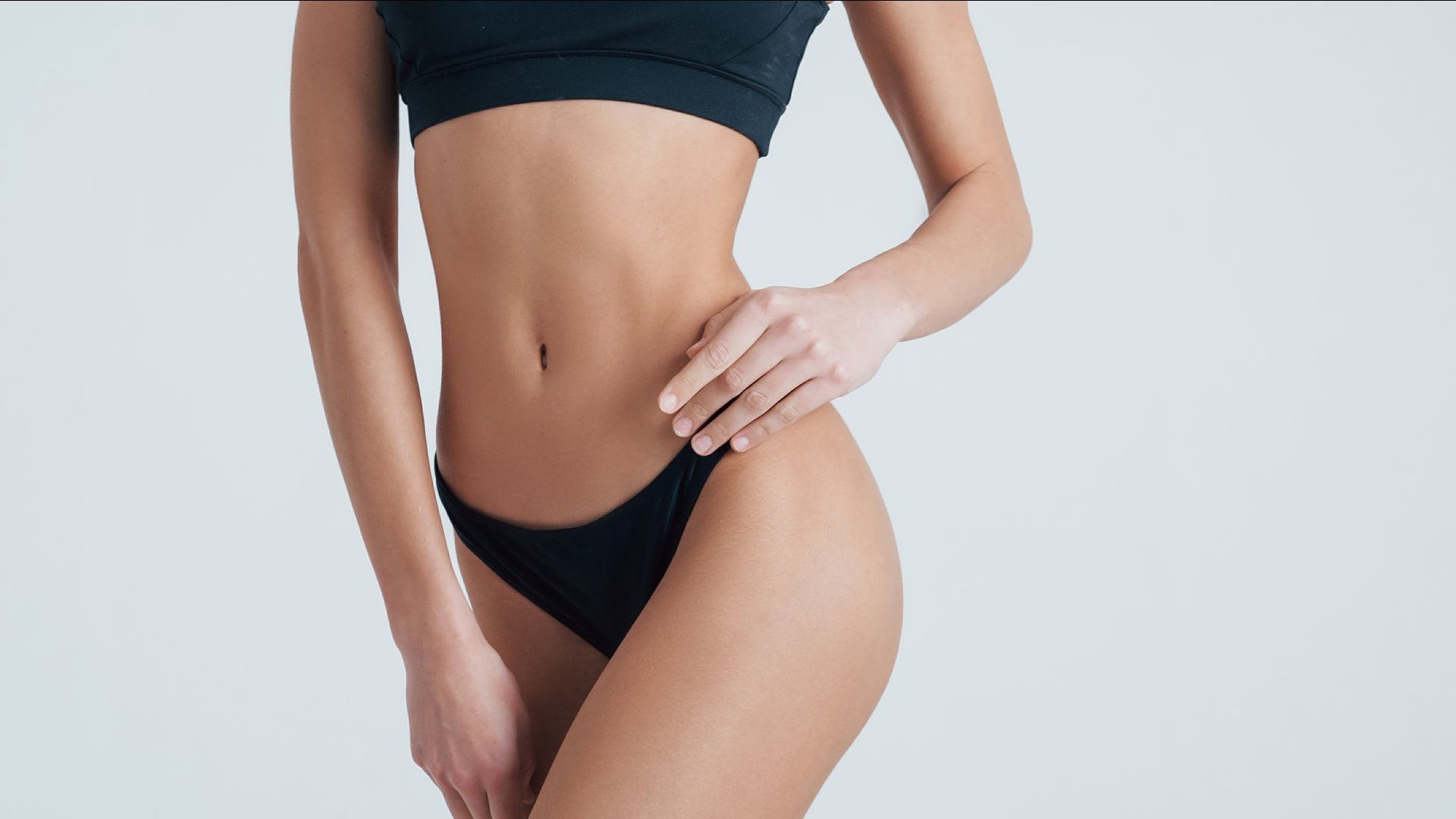 A woman in a black bikini is standing with her hand on her hip.