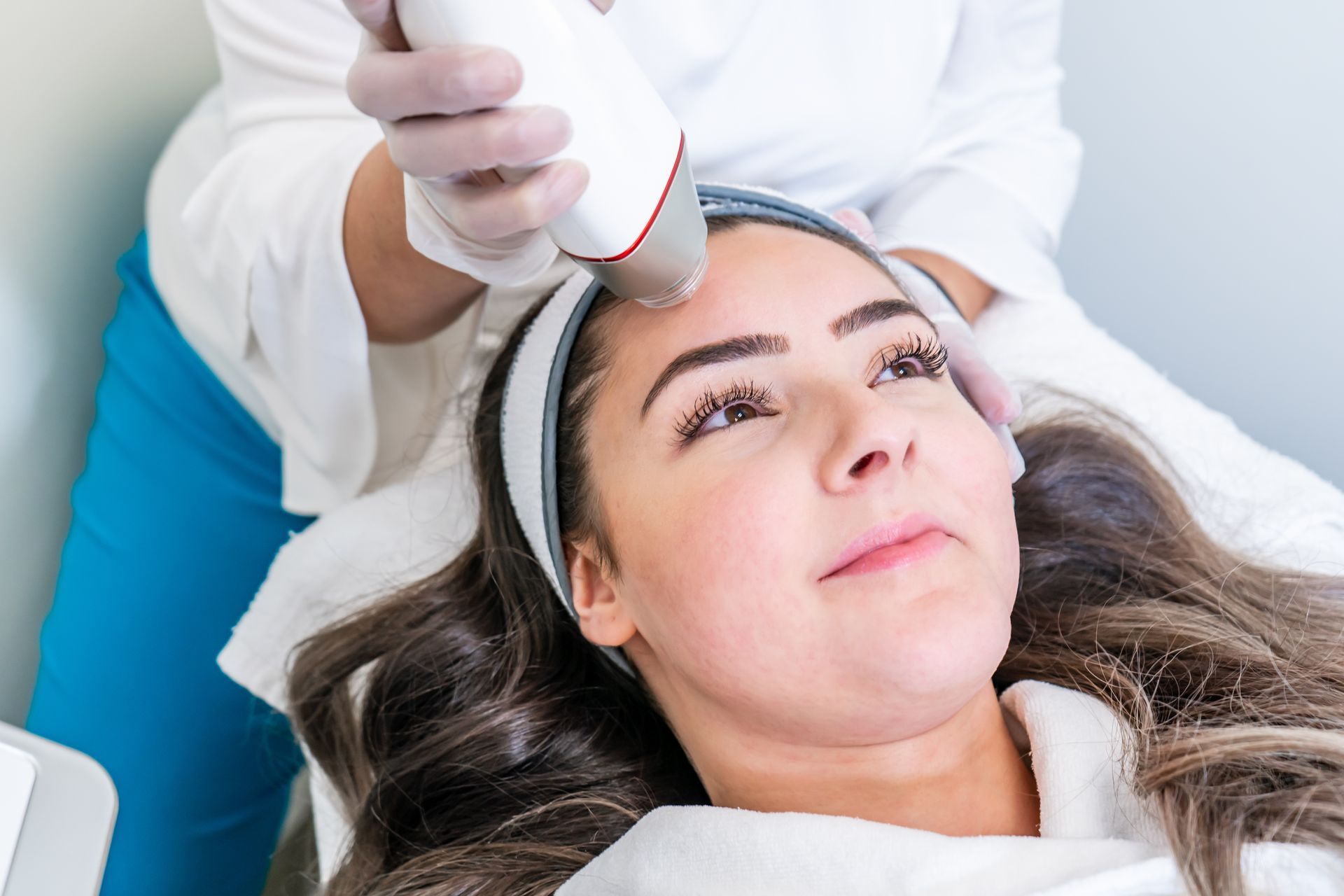 Woman receiving facial treatment with a handheld device in a spa setting