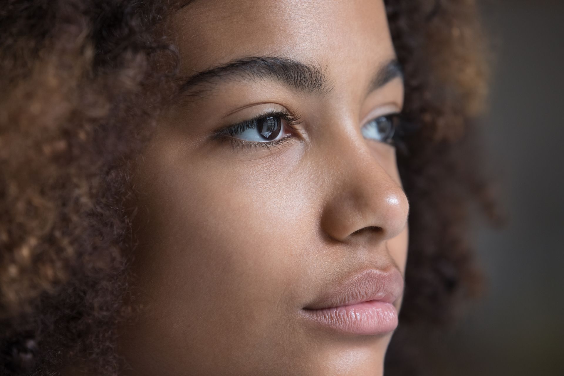 A close up of a woman 's face with curly hair.