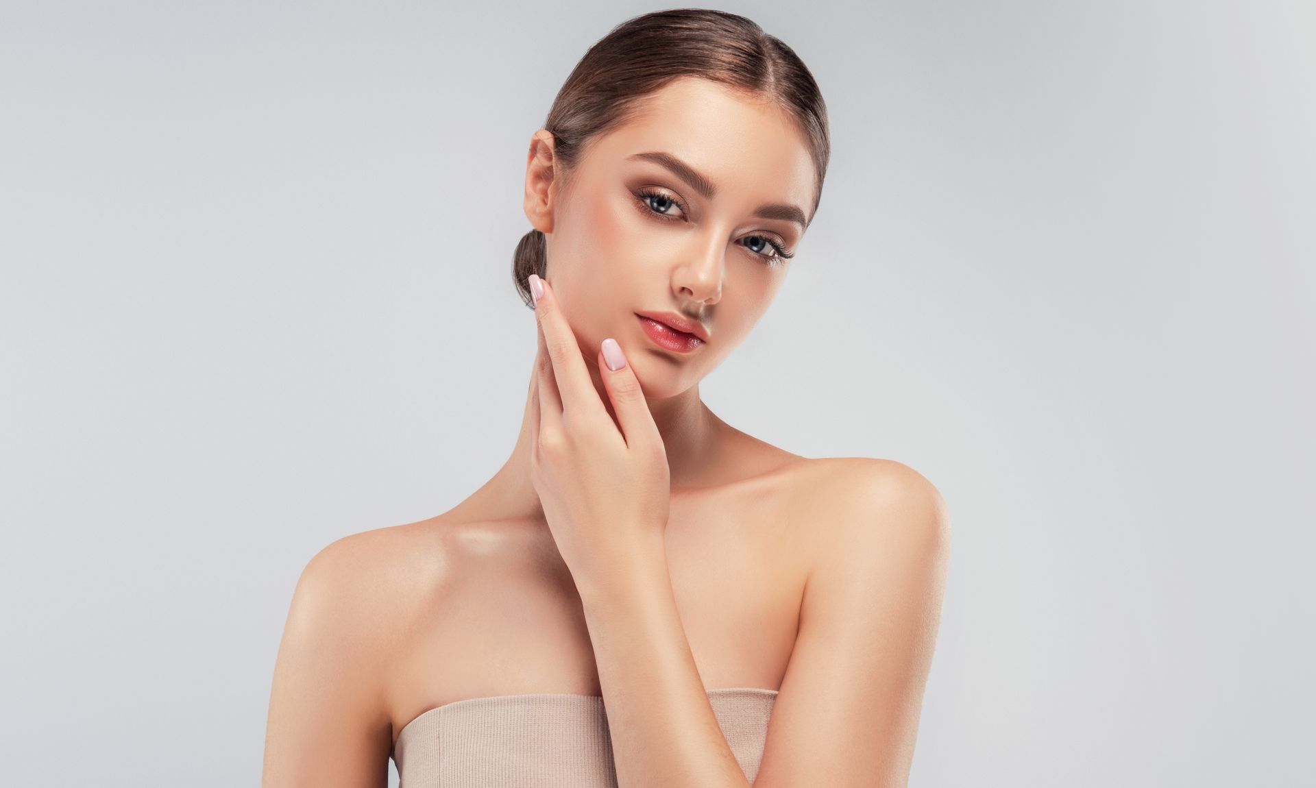 A woman is touching her face with her hand and looking at the camera.