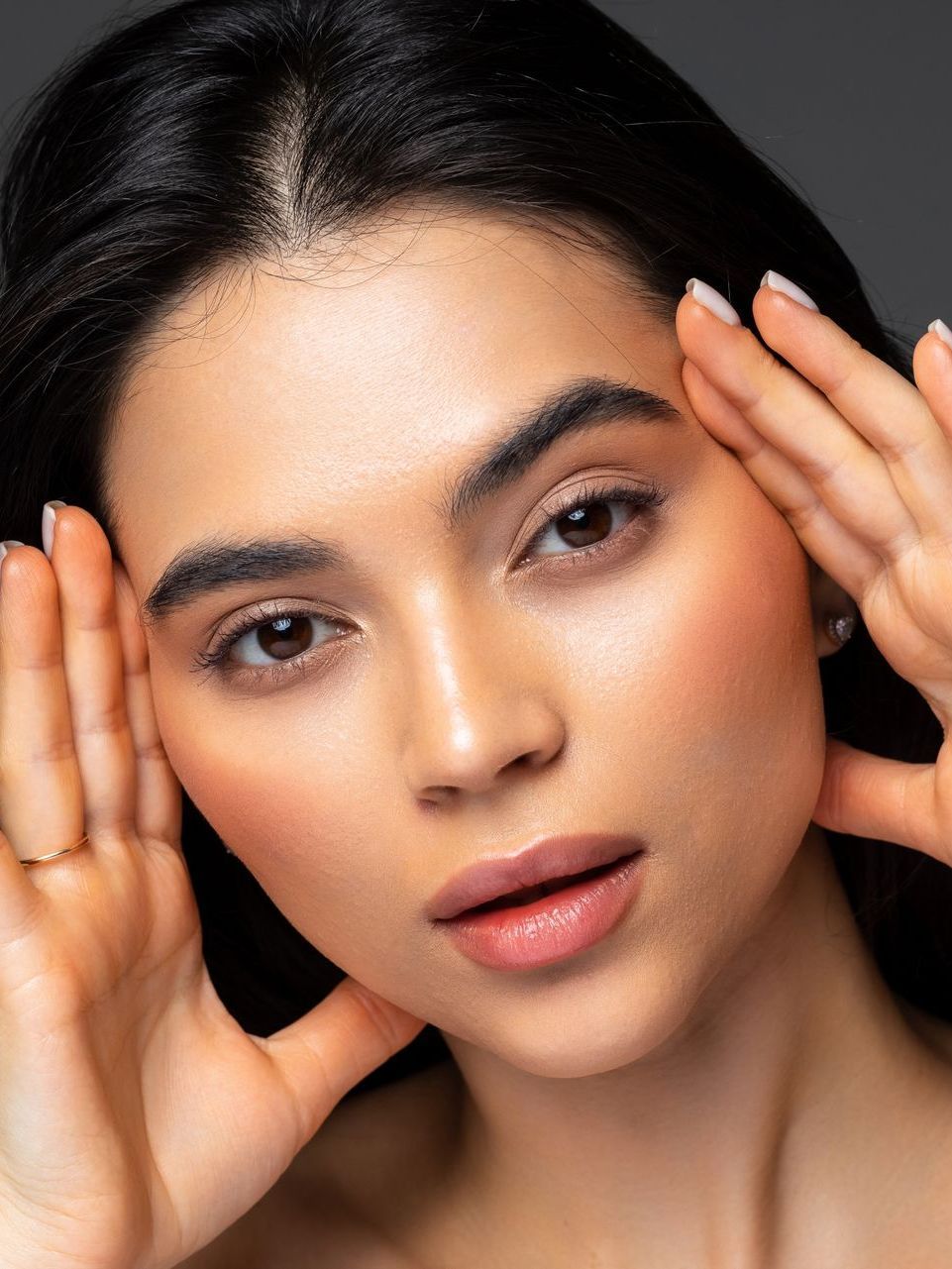 A close up of a woman covering her ears with her hands.