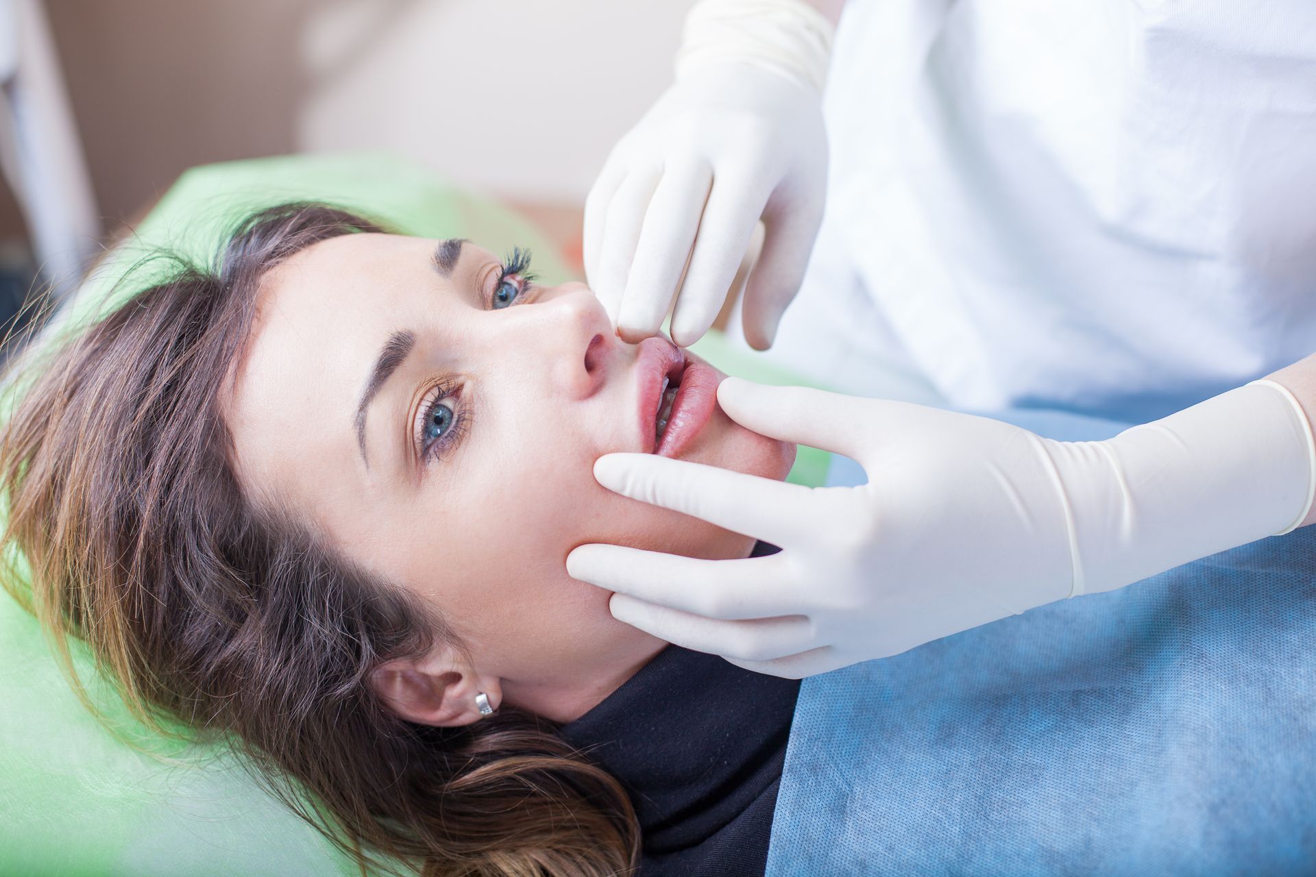A woman is getting her lips pierced by a dentist.