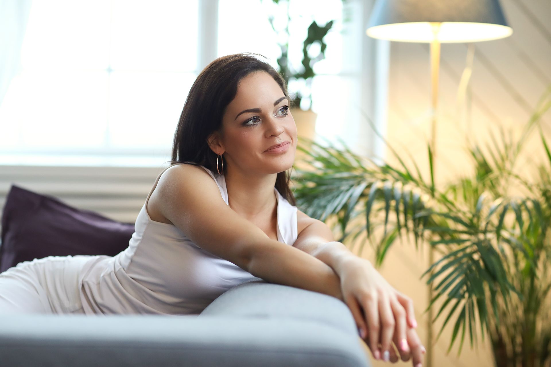 A woman is laying on a couch in a living room.