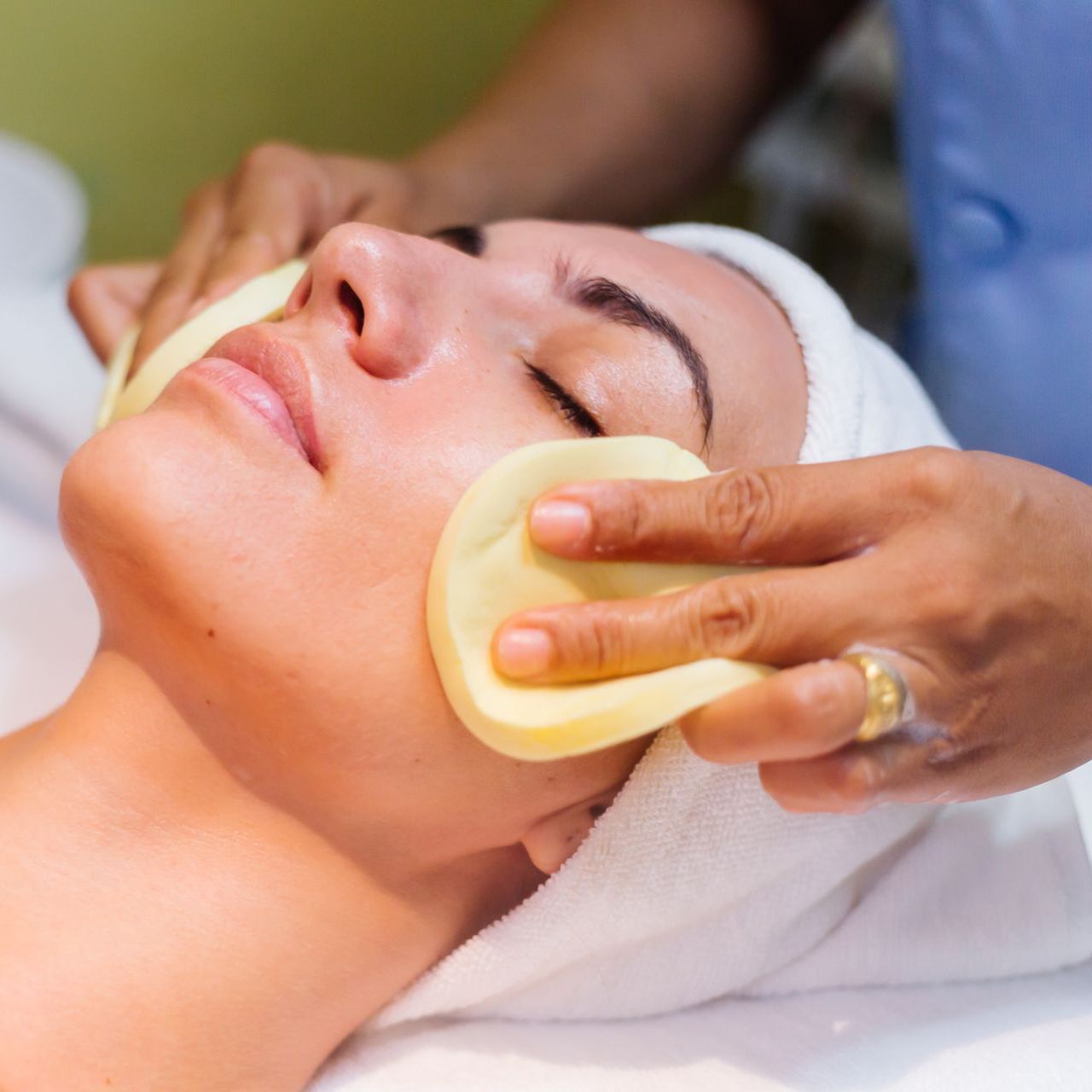 A woman with a towel wrapped around her head is getting a facial treatment.