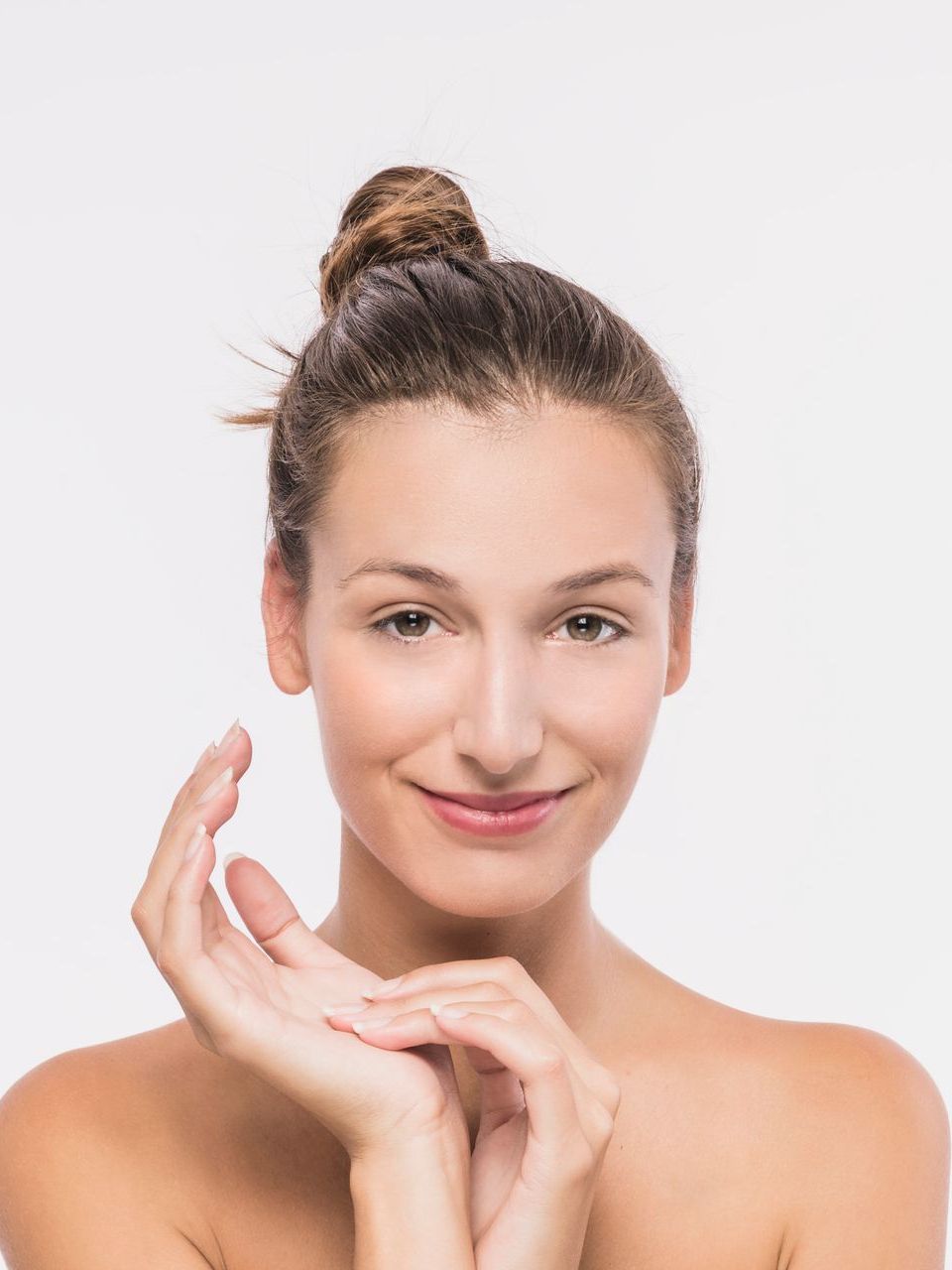A woman is touching her face with her hands and smiling.