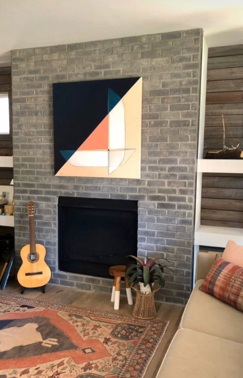 A living room with a fireplace , couch , guitar and painting on the wall.