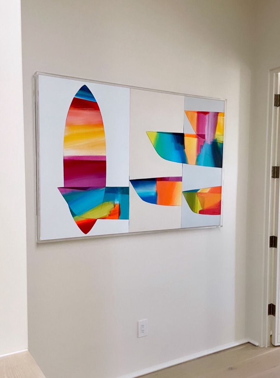 A large colorful painting is hanging on a white wall.