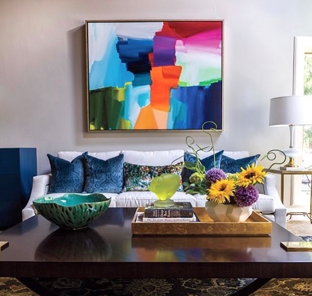A colorful painting hangs above a couch in a living room