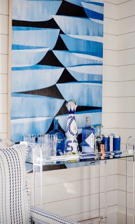 A room with a painting on the wall and a bar cart