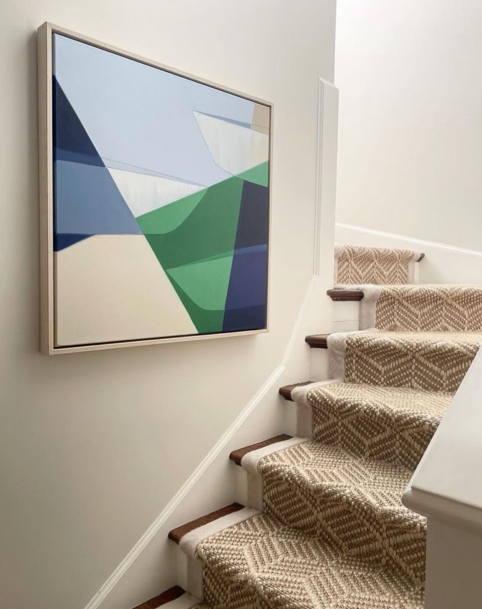 A painting is hanging on a wall above a set of stairs.