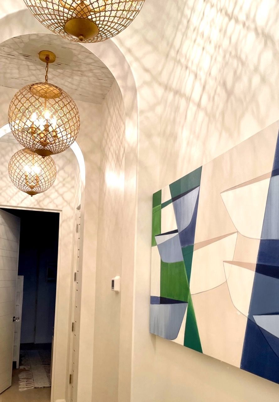 A hallway with a painting on the wall and a chandelier hanging from the ceiling