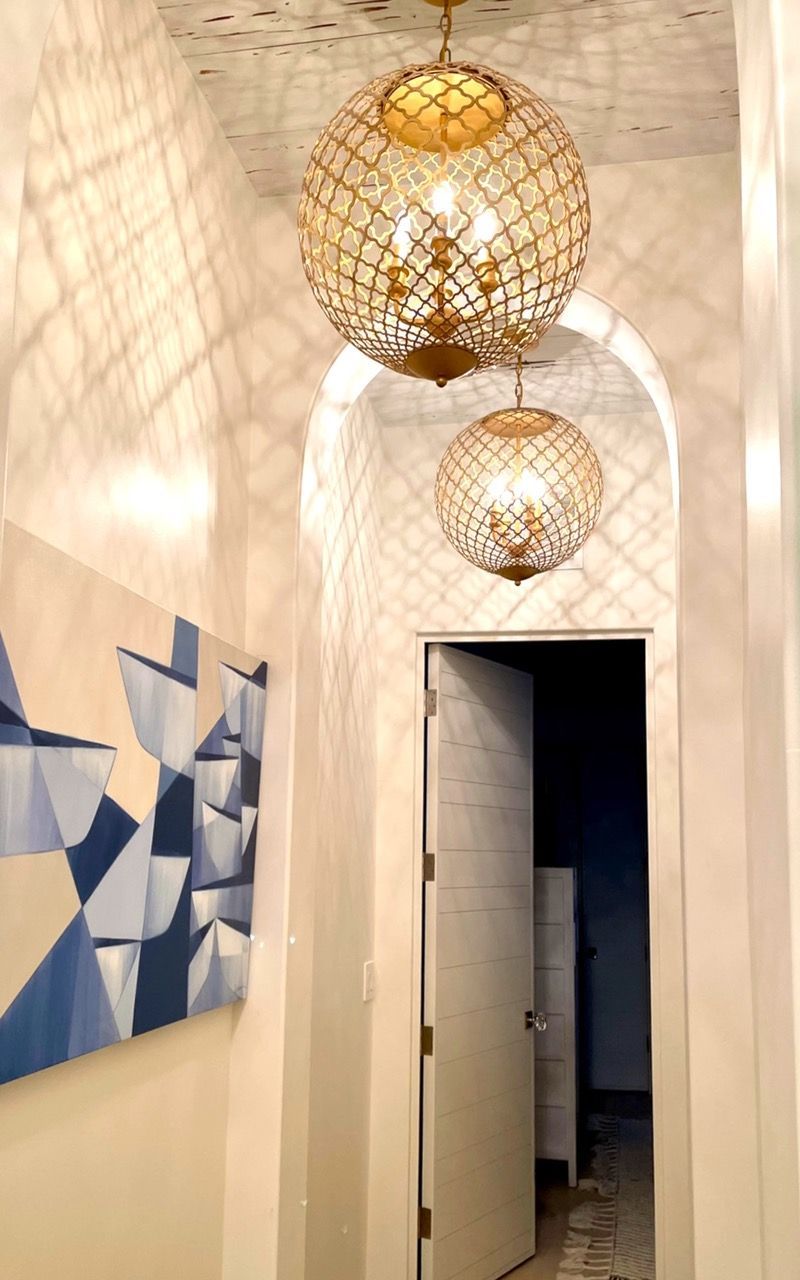 A hallway with two chandeliers hanging from the ceiling