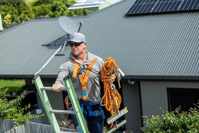 A Man On A Ladder Working On Installing Solar Panels — Solar Power Whitsunday In Midge Point, QLD