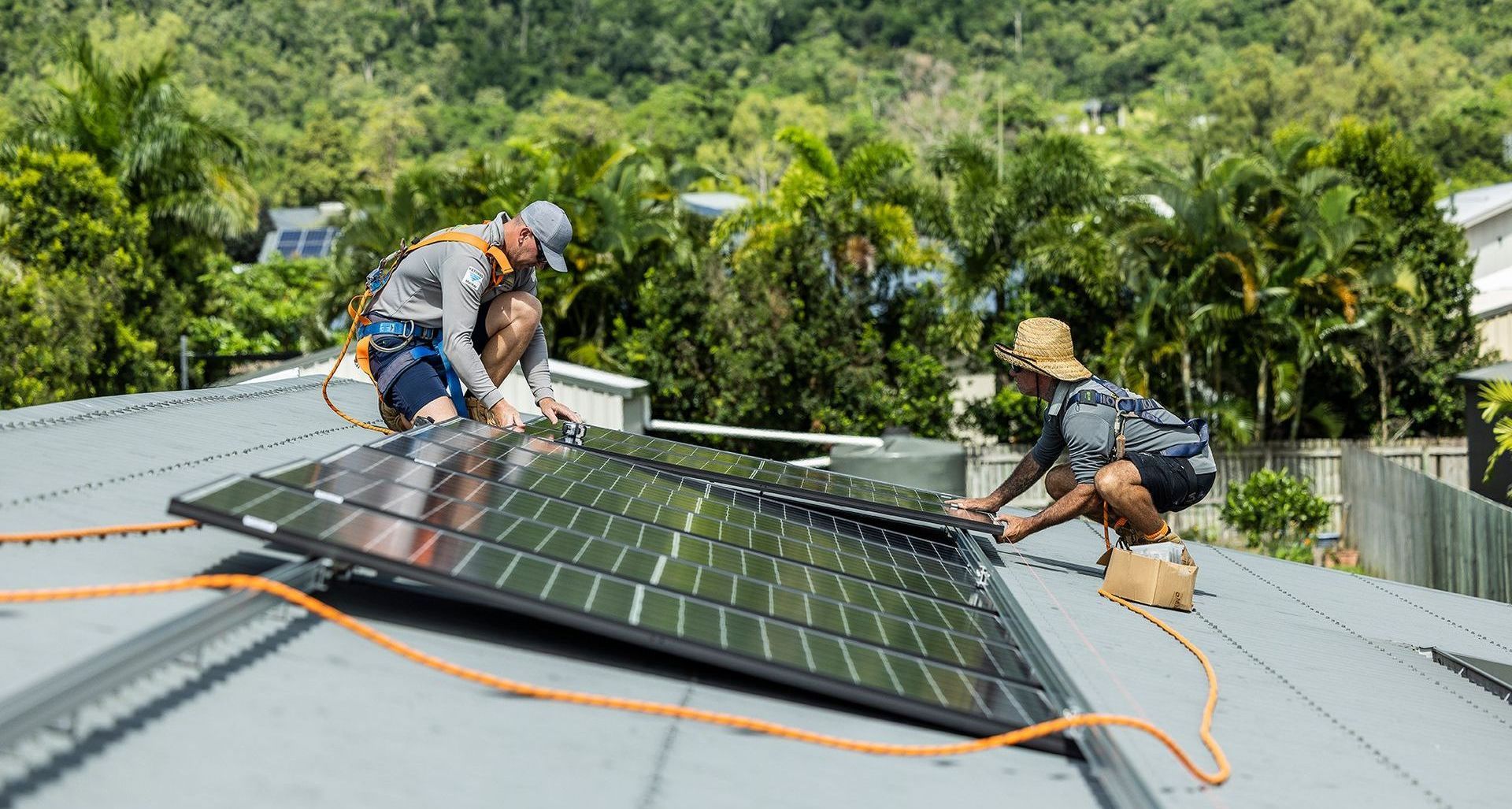 Two Workers Installing Solar Panels on a Roof Surrounded by Trees — Solar Power Whitsunday In Cannon Valley, QLD