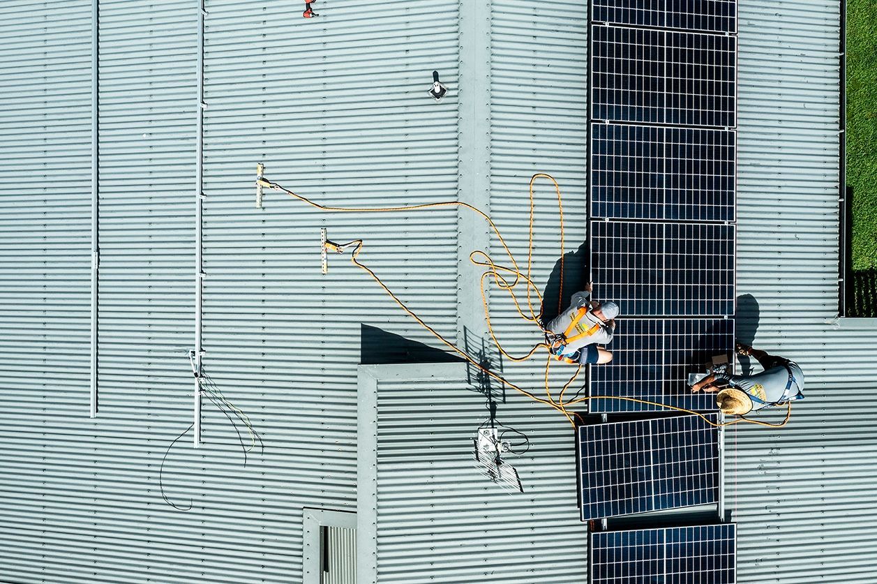 Workmen Installing A Row Of Solar Panels On Top Of A Roof — Solar Power Whitsunday In Cannon Valley, QLD