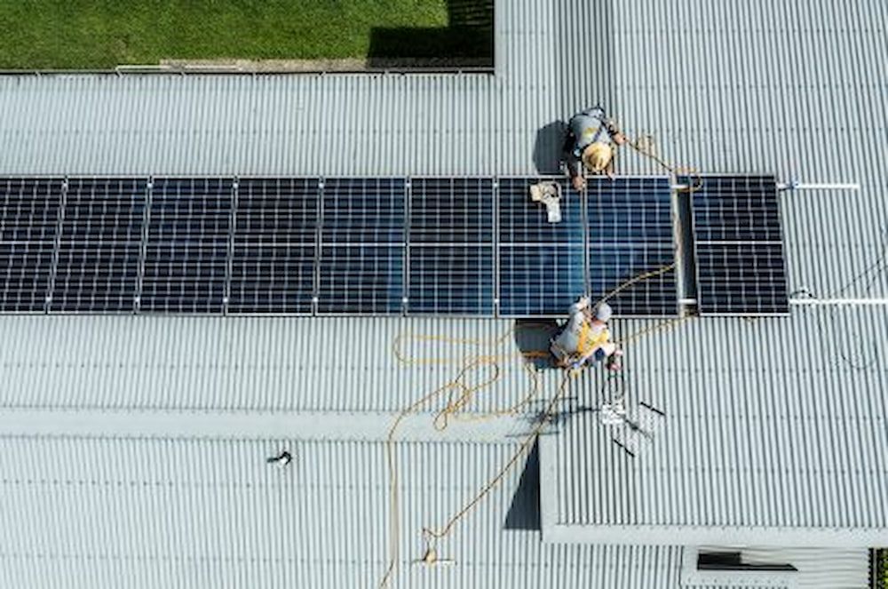 A Group Of People Are Installing Solar Panels On The Roof Of A Building — Solar Power Whitsunday In Bowen, QLD