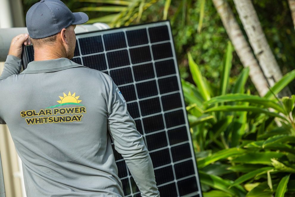 A Person Is Standing On Top Of A Roof With Solar Panels On It — Solar Power Whitsunday In Cannon Valley, QLD