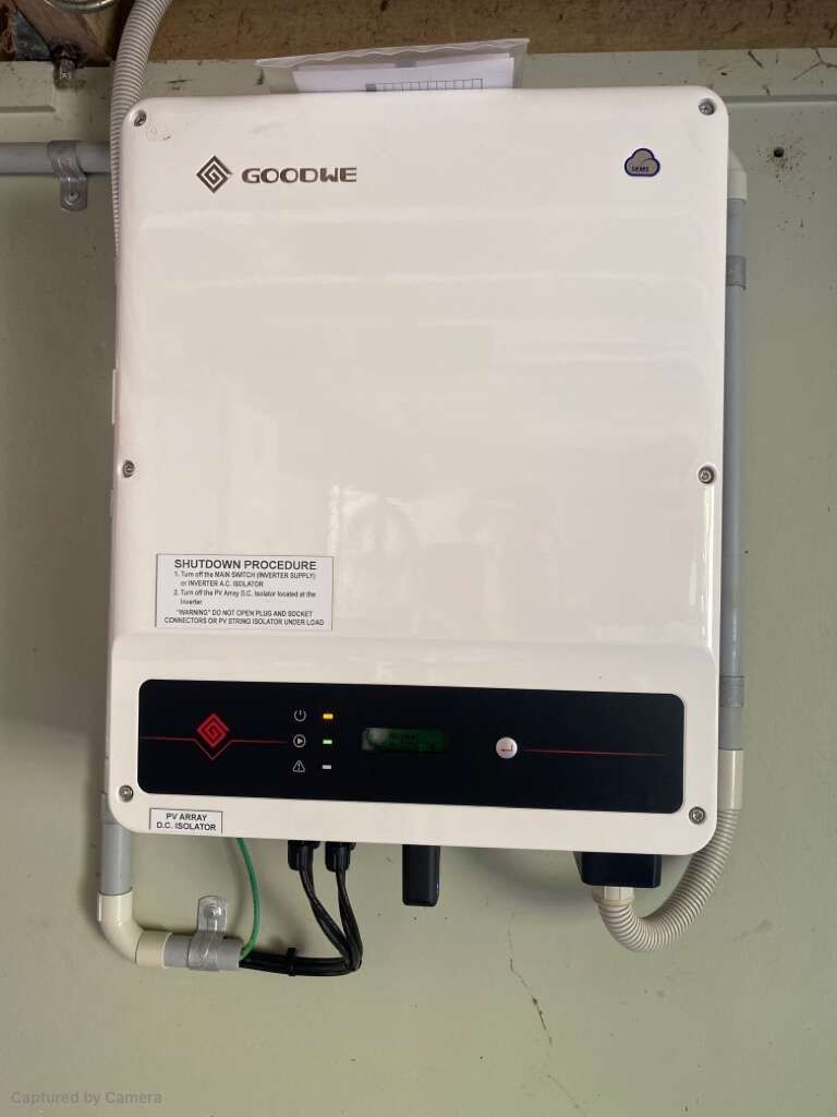 A Man Is Installing A Solar Inverter On A Wall — Solar Power Whitsunday In Airlie Beach, QLD
